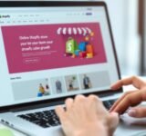 Laptop with Shopify interface and shopping bags nearby.